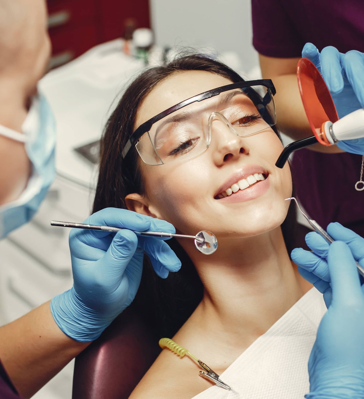Dentist and assistant treating smiling patient in chair